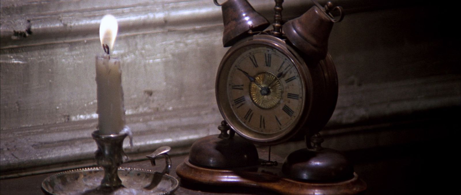 an old fashioned clock sitting next to a candle