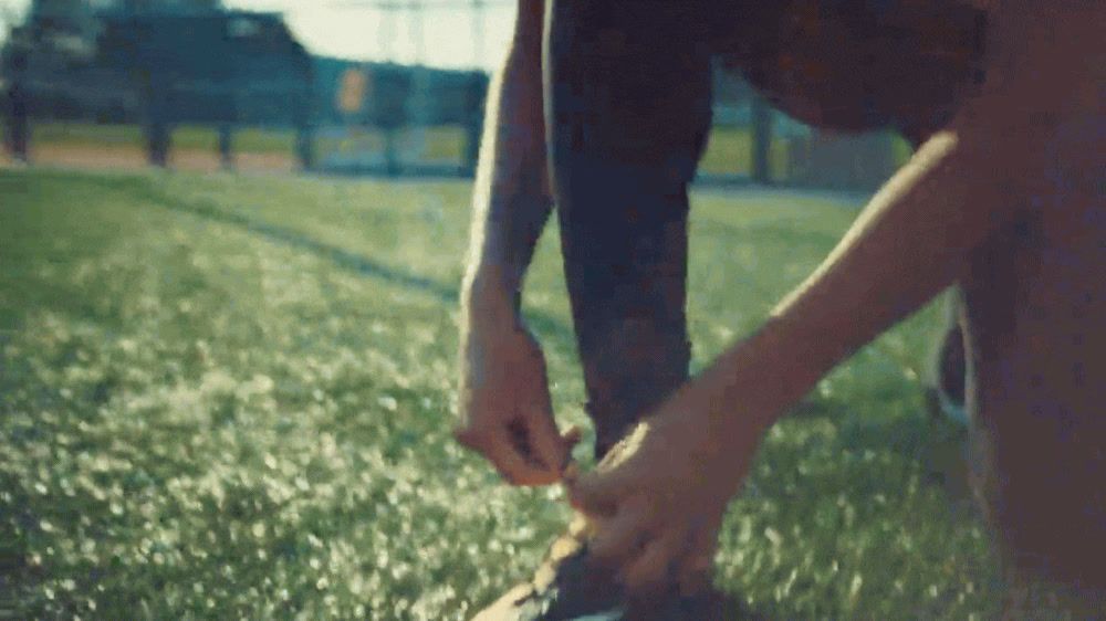 a person tying a pair of shoes in the grass