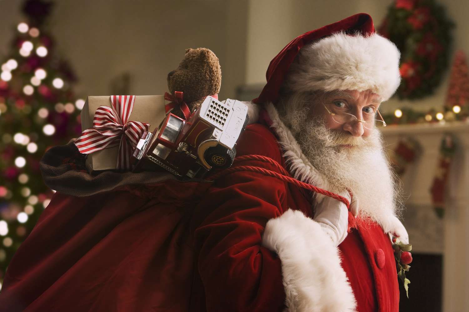 a man in a santa suit carrying a teddy bear