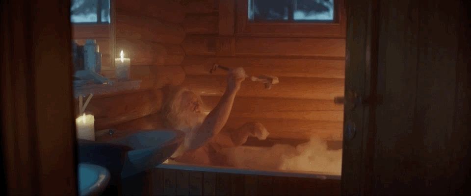 a woman sitting in a bathtub with candles on the side of it