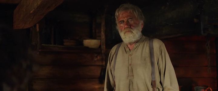 a man with a white beard standing in a room