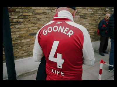 a man in a red and white vest walking down a street