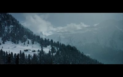 a mountain covered in snow and trees under a cloudy sky