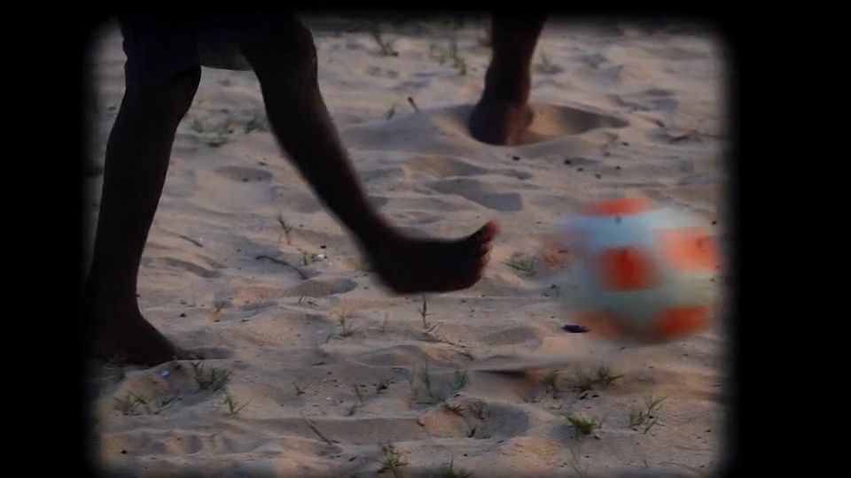 a person kicking a soccer ball in the sand