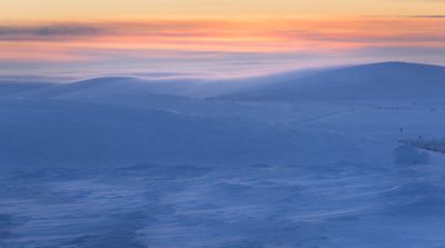 a snow covered hill with a sunset in the background