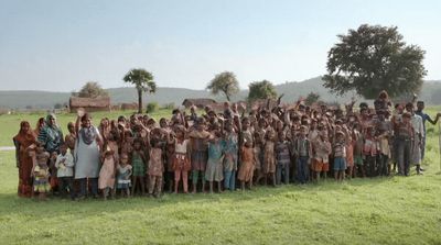 a group of people standing next to each other on a lush green field