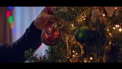 a person decorating a christmas tree with ornaments