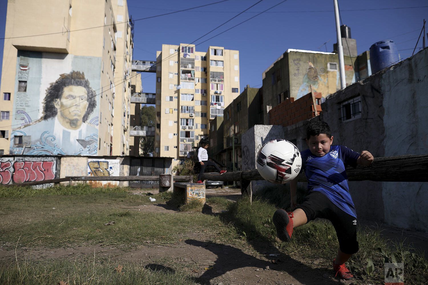 a young boy holding a soccer ball in front of a building