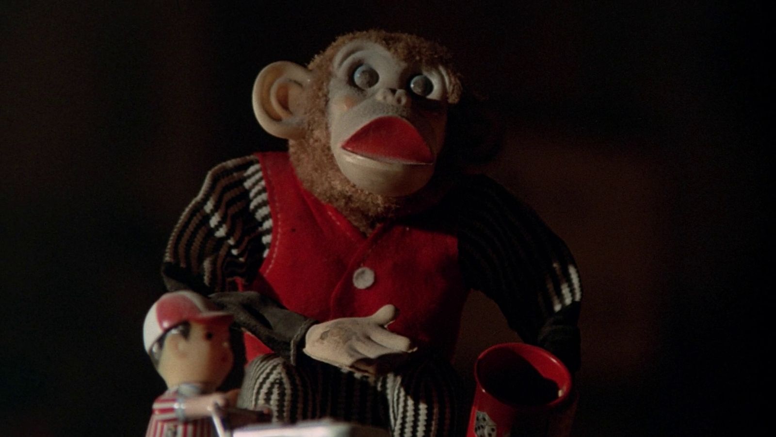 a stuffed monkey with a red hat and striped shirt