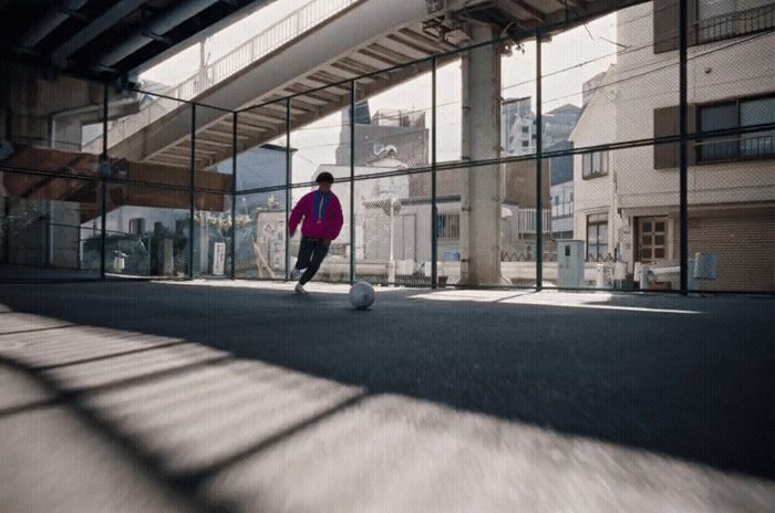 a person in a pink jacket kicking a soccer ball