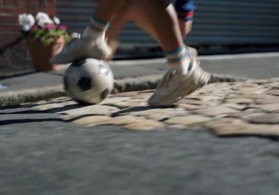 a person kicking a soccer ball on a street