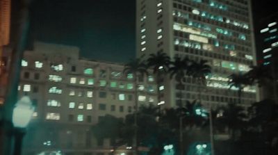 a city street at night with a tall building in the background