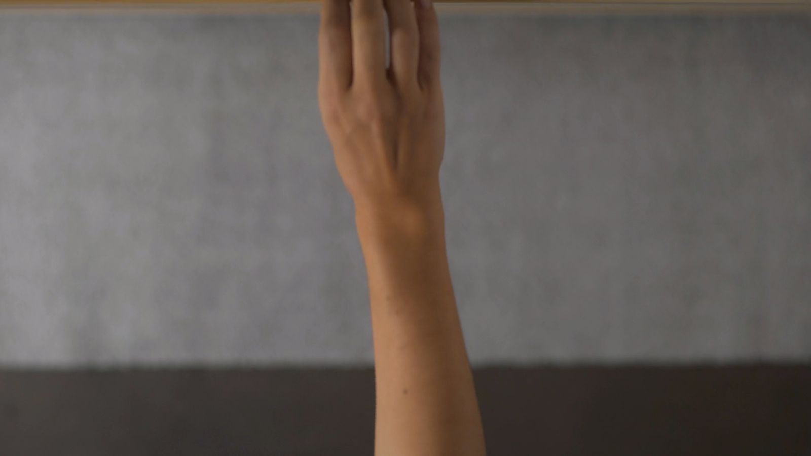 a woman's hand holding a wooden object above her head