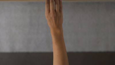 a woman's hand holding a wooden object above her head