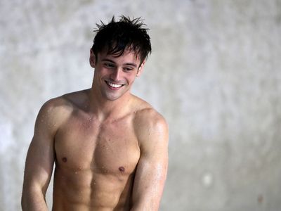 a shirtless young man standing next to a white wall