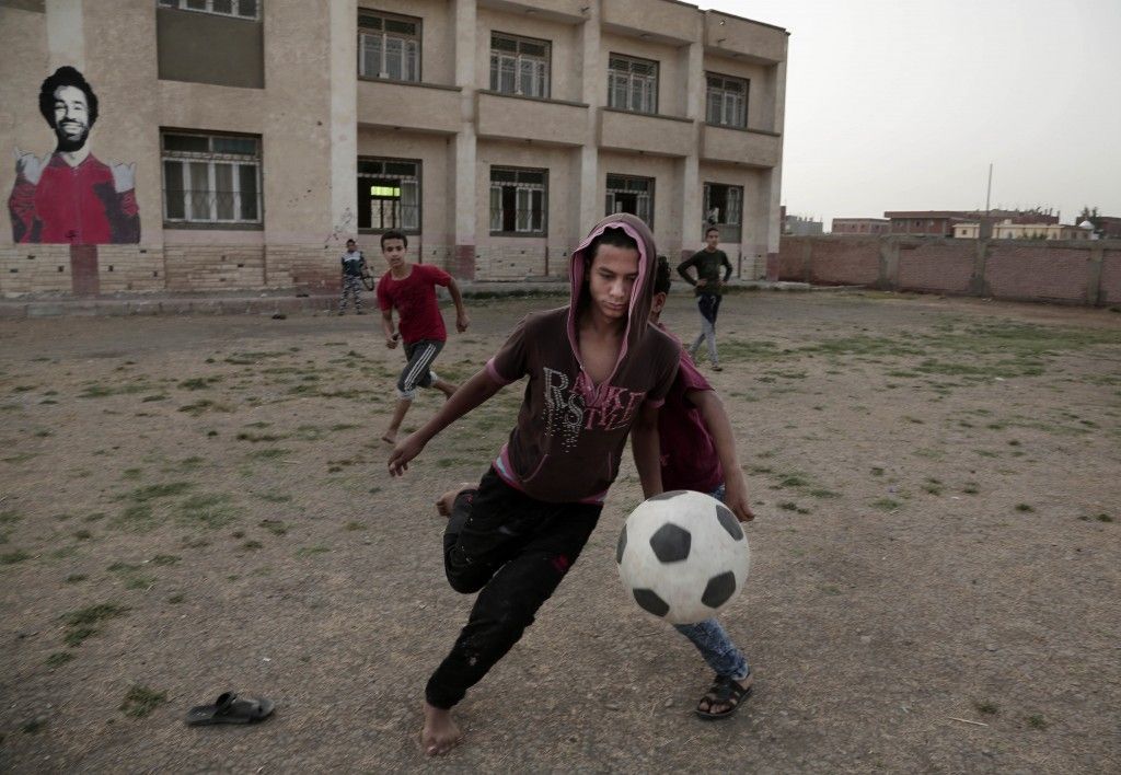 a young man kicking a soccer ball in front of a building