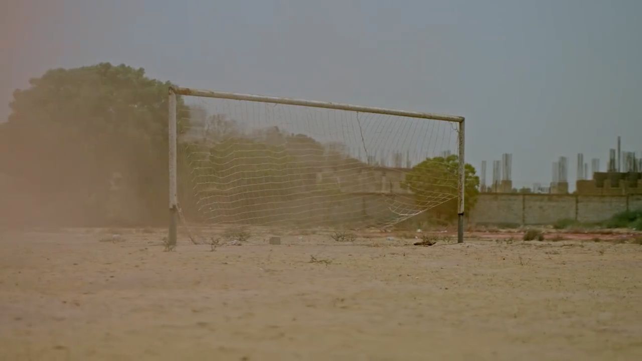 a soccer goal sitting in the middle of a dirt field