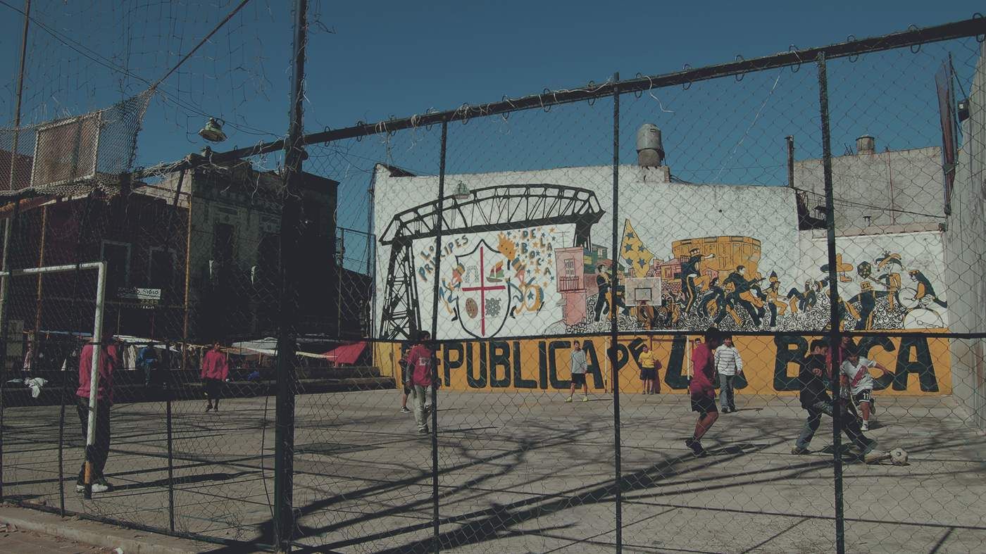 a group of people walking down a street next to a fence