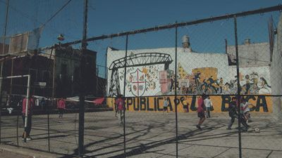 a group of people walking down a street next to a fence