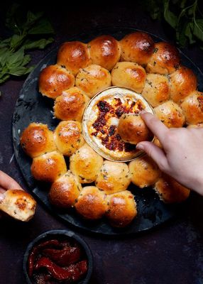 a plate of bread rolls with a bowl of dip