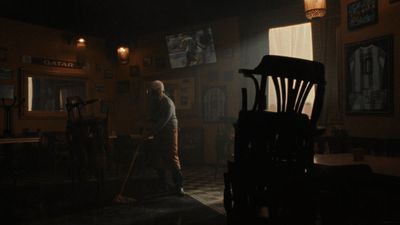 a man standing in a dark room next to a chair