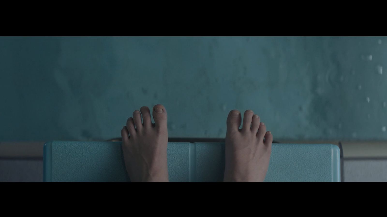 a person's bare feet standing on a blue surface