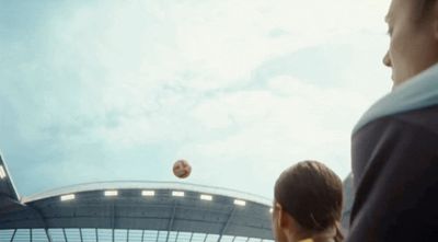 a man and a woman watching a soccer ball in the air