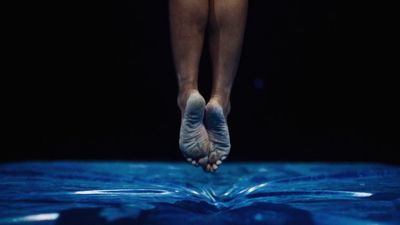 a person standing on a bed with their feet in the air