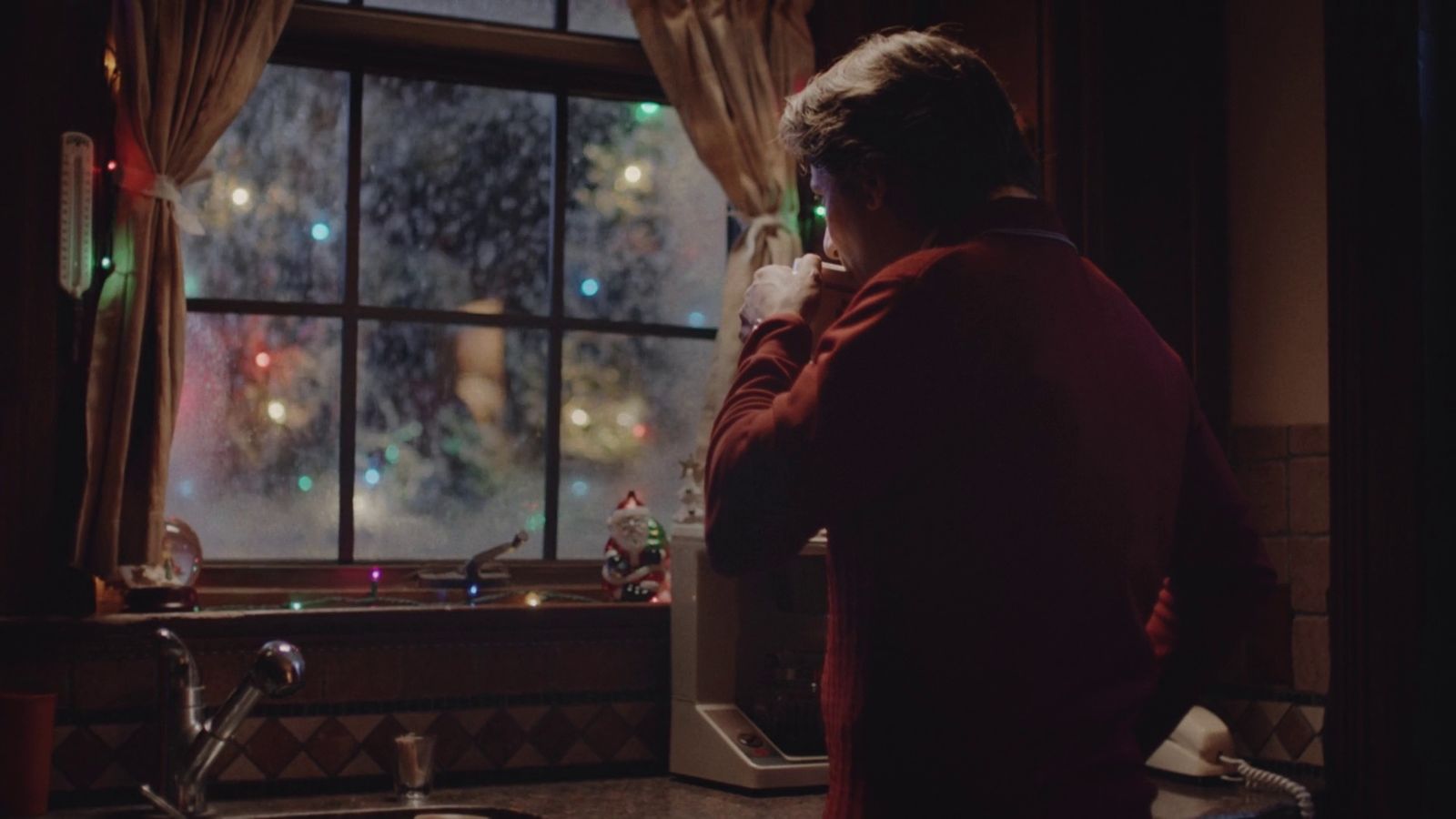 a man standing in a kitchen next to a window