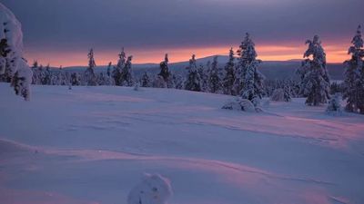 the sun is setting over a snowy mountain