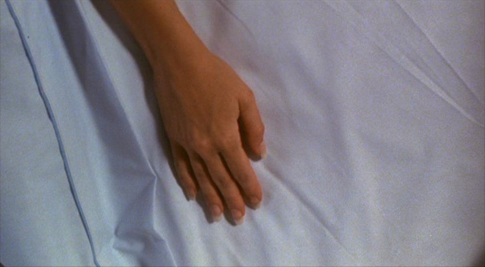 a person's hand resting on a white sheet