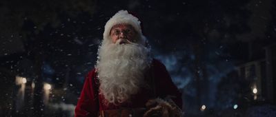 a man dressed as santa claus standing in the snow