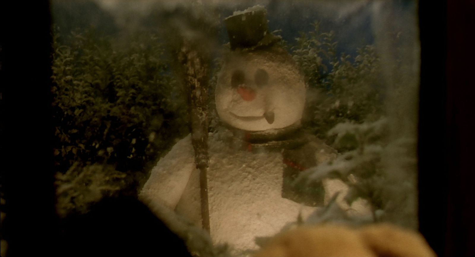 a snowman is seen through a glass window