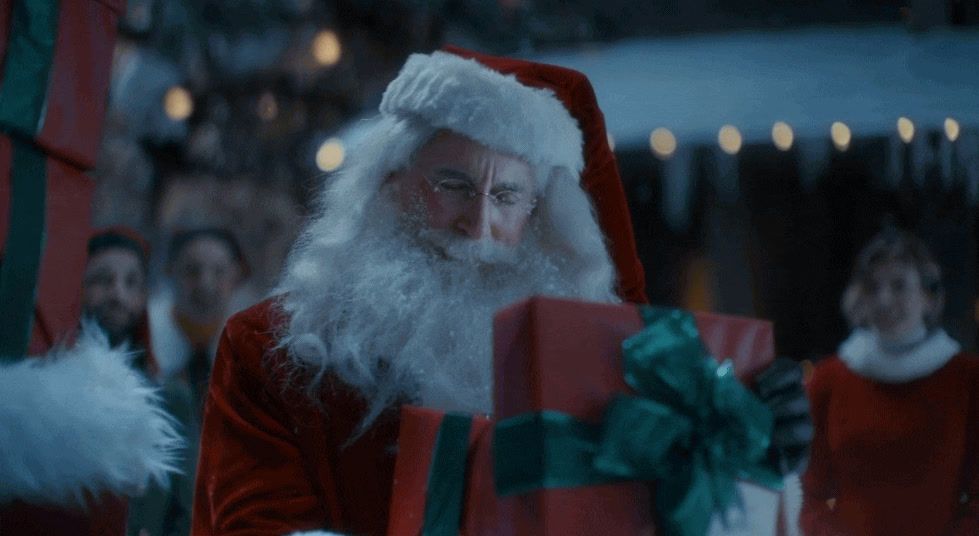 a man dressed as santa claus holding a large present