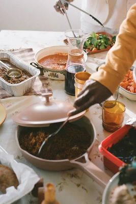 a table full of food with a person holding a spoon