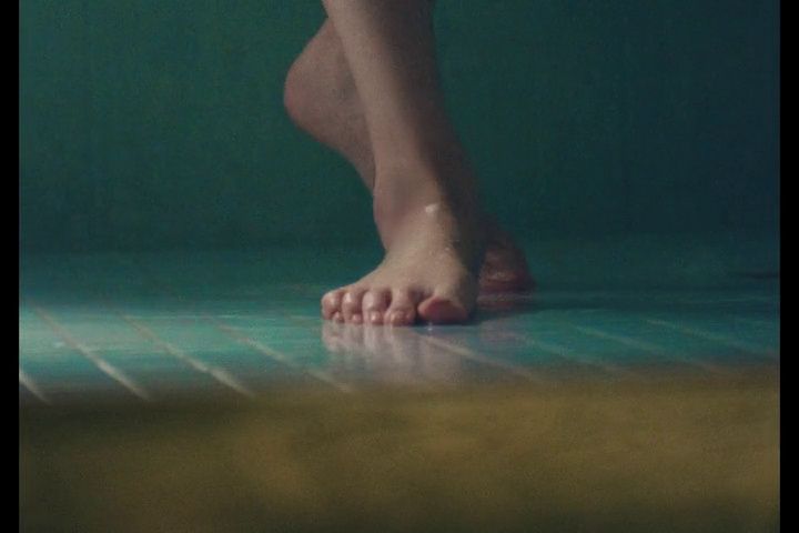 a person standing on a tiled floor with their bare feet