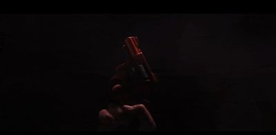 a hand holding a red gun in the dark