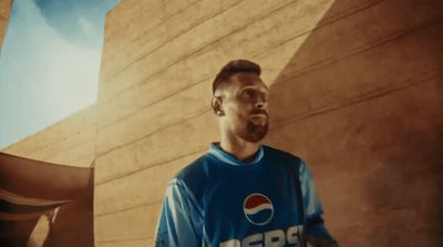 a man standing in front of a building wearing a pepsi shirt