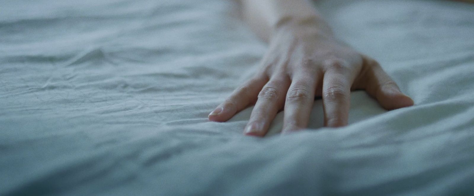 a person's hand resting on a white sheet