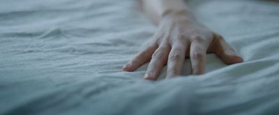 a person's hand resting on a white sheet