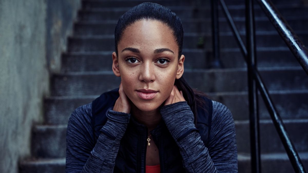 a woman with her hands on her face sitting on a set of stairs