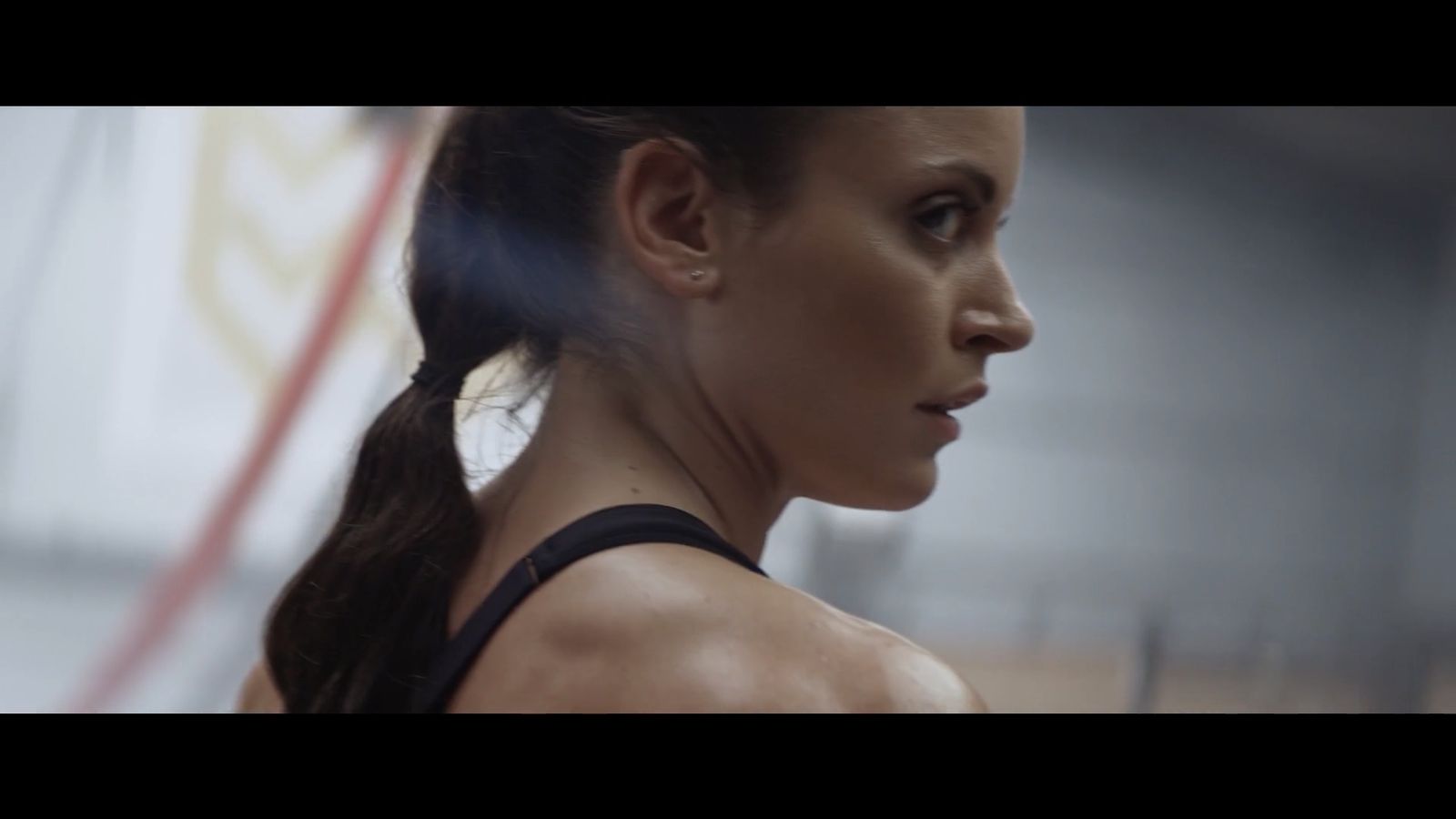 a woman with a ponytail standing in a gym