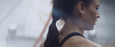 a woman with a ponytail standing in a gym