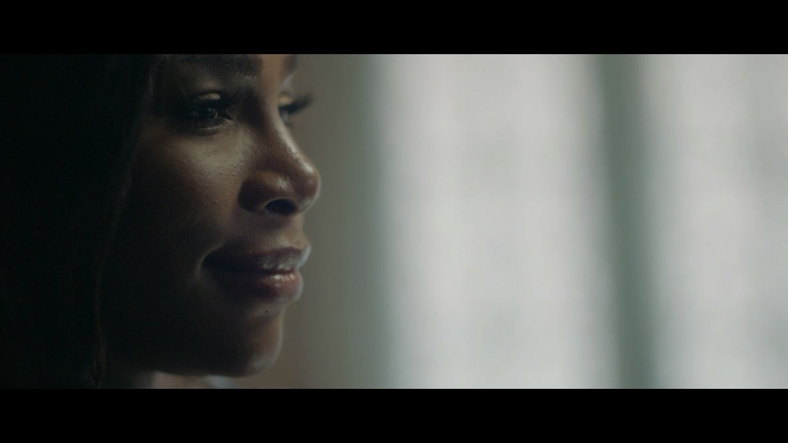 a close up of a woman's face with a curtain in the background