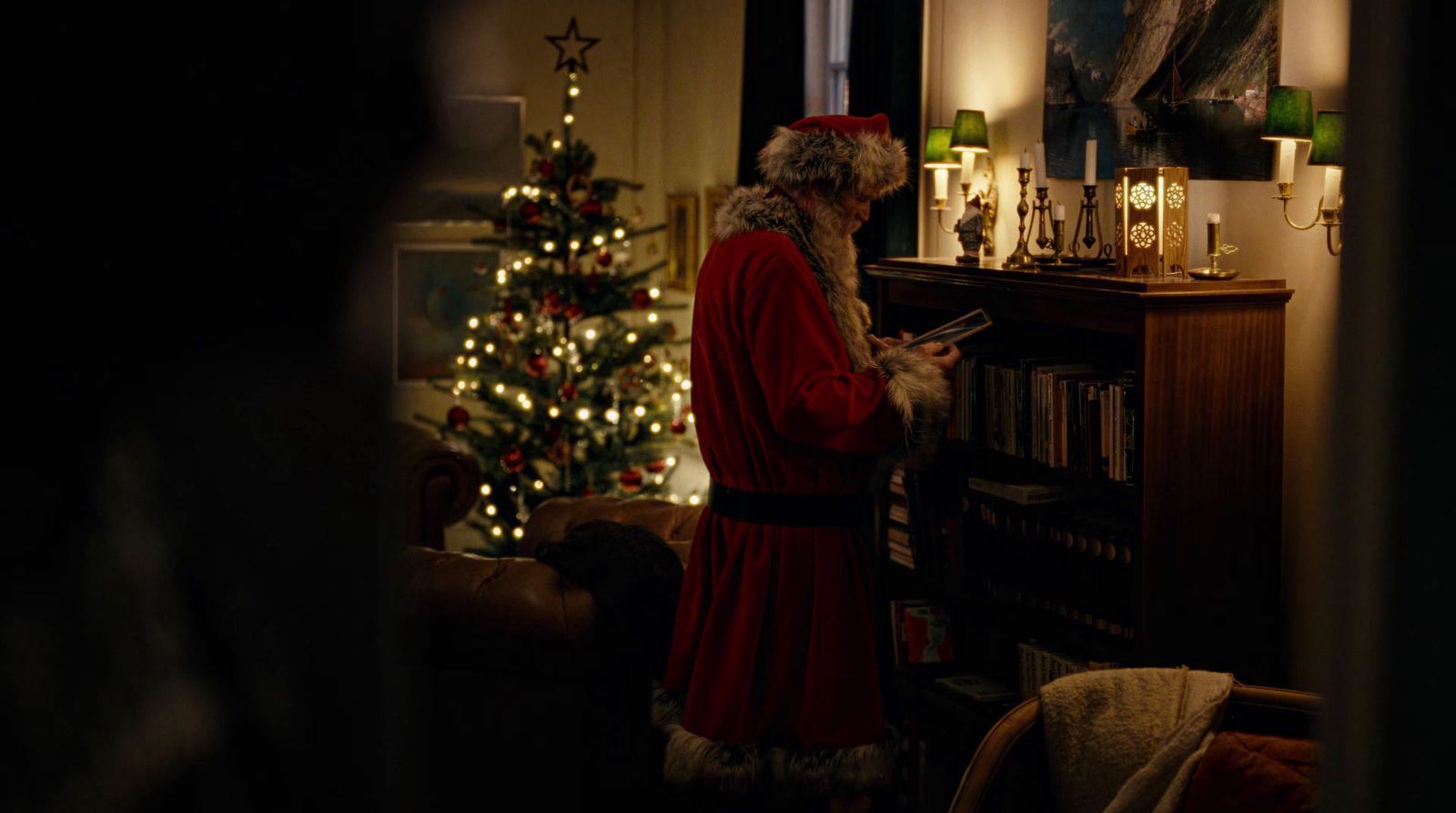 a man dressed as santa claus standing in front of a christmas tree