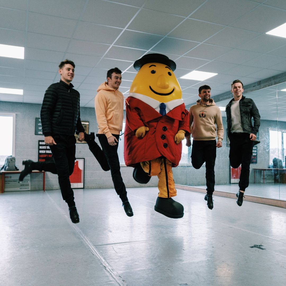 a group of young men standing around a mascot