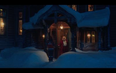 a man and a woman standing outside of a house in the snow