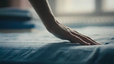 a person's hand on top of a bed