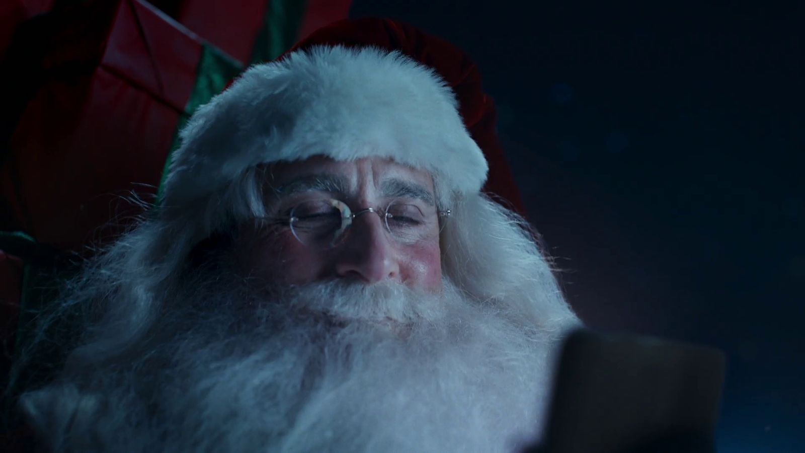 a man dressed as santa claus looking at a cell phone