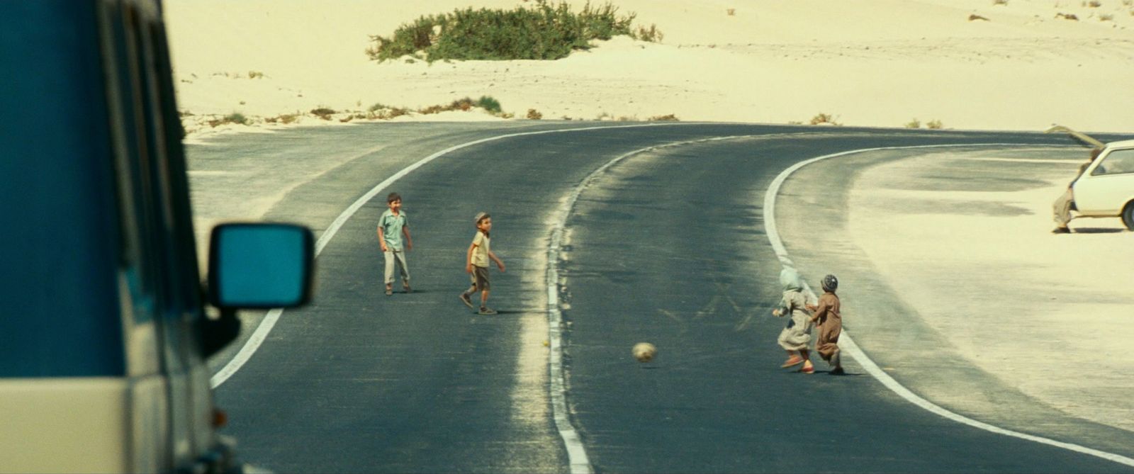 a group of people walking down a road next to a car